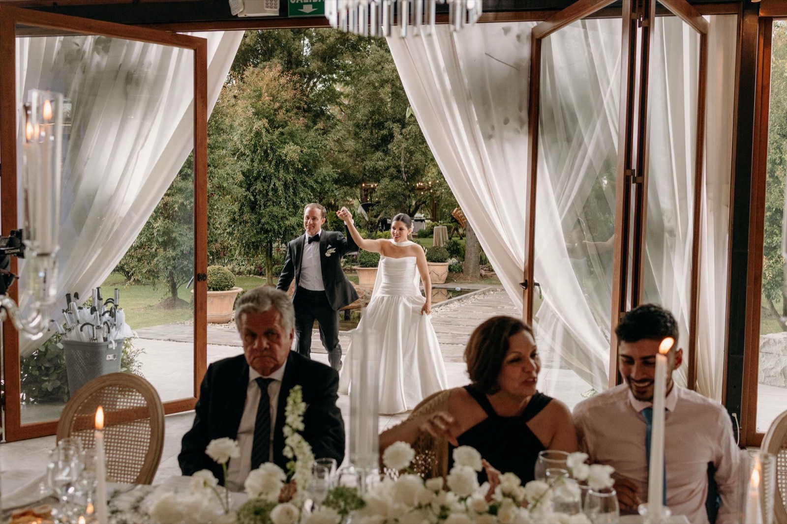 Novios junto a los padrinos entre cortinas de tul