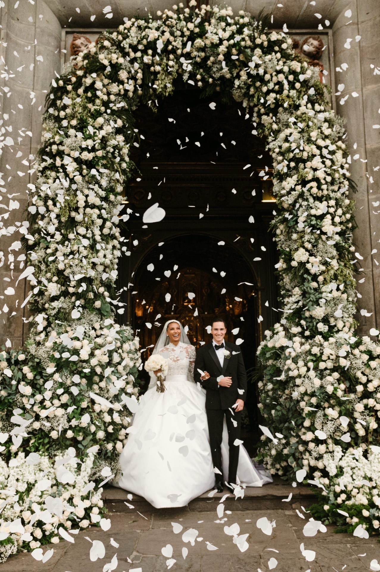 Novios abrazados bajo arco floral
