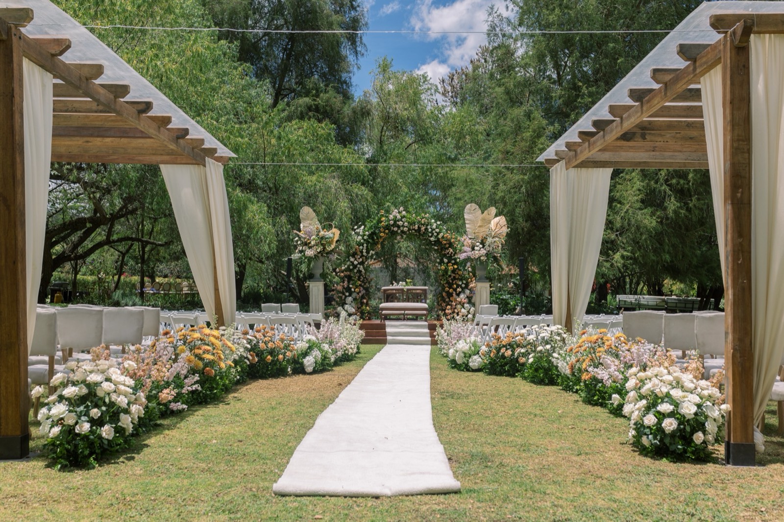Pasillo de ceremonia bajo pérgola con flores