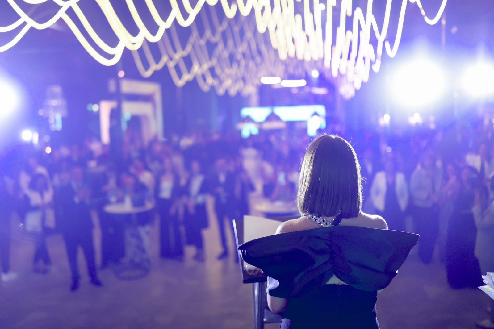 Asistentes en evento corporativo con iluminación de producción