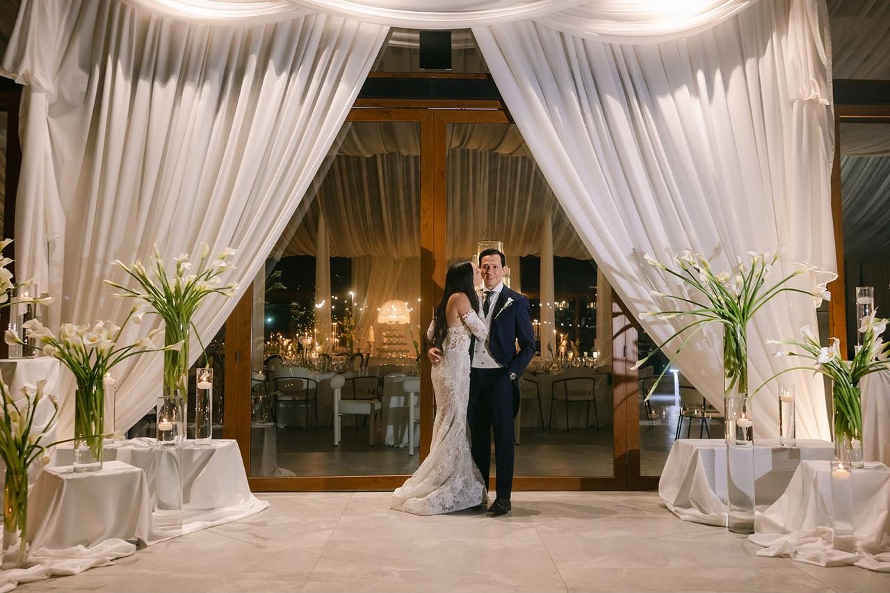 Novios en la entrada de la recepción decorada con azucenas