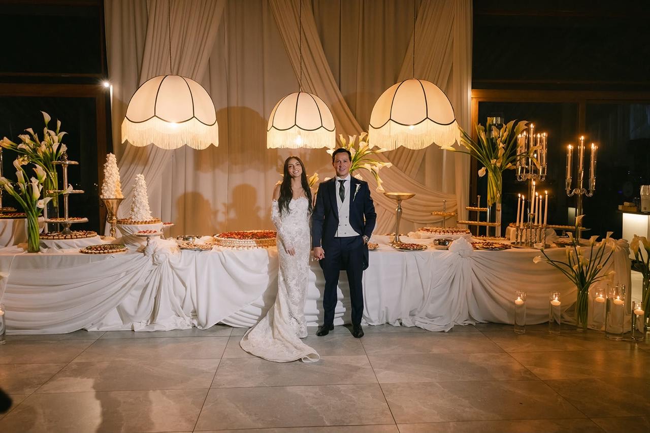 Novios junto a la mesa de postres en la recepción