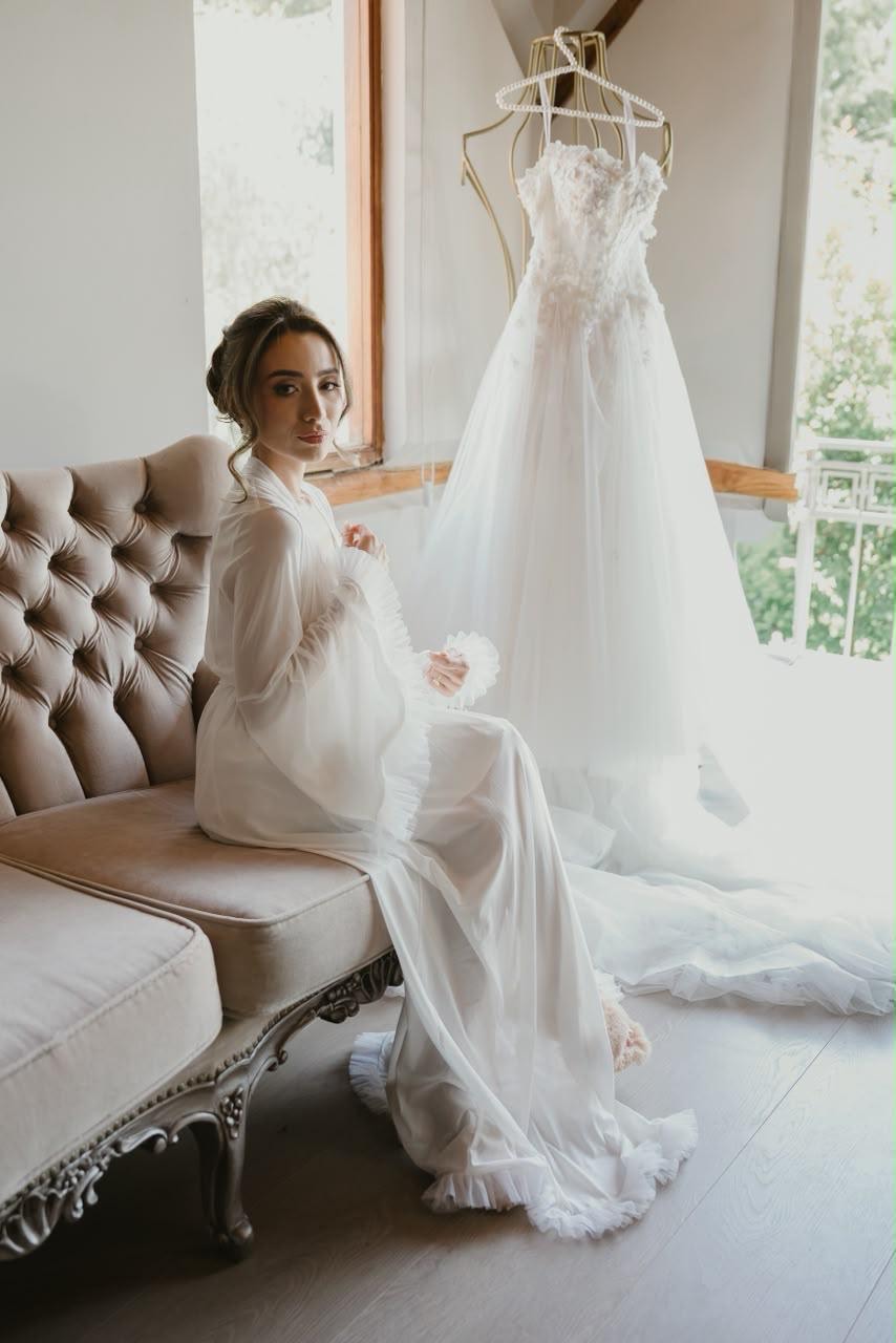 Novia preparándose junto a su vestido de novia