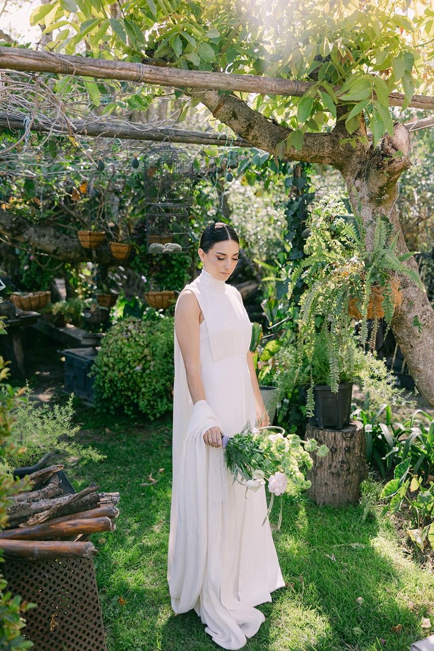 Novia posando bajo pérgola con flores en el jardín