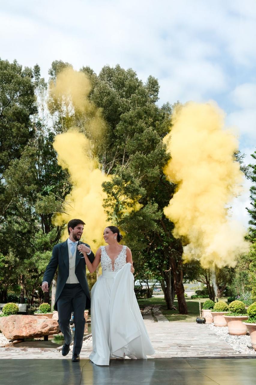 Novios caminando entre humo de color al finalizar la ceremonia