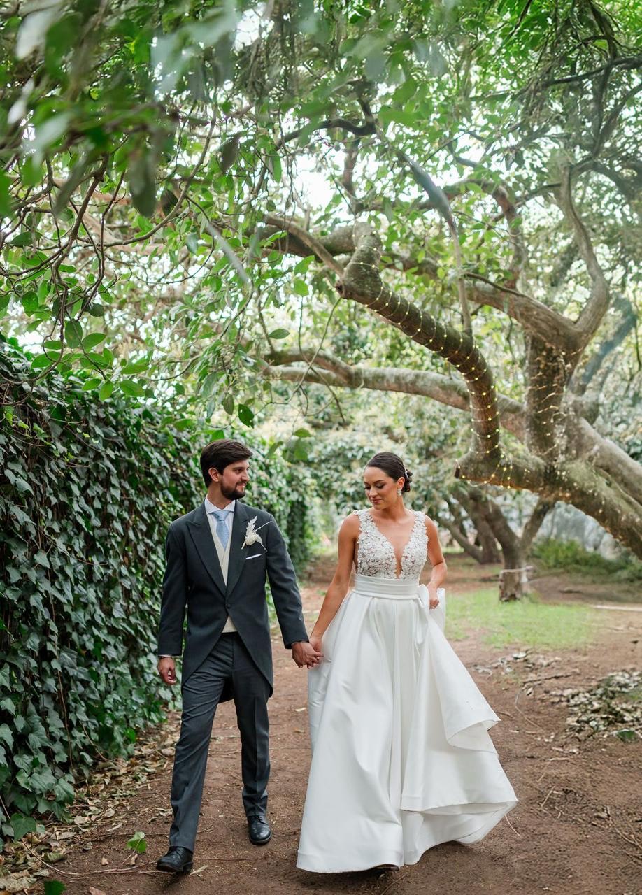 Novios caminando tomados del brazo por el jardín