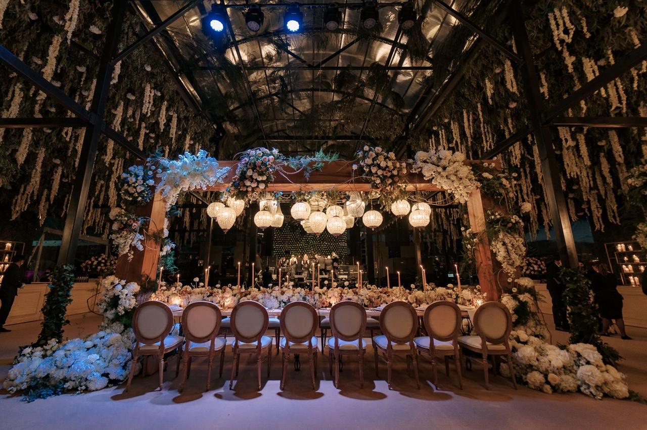 Mesa de banquete con arco floral y luces colgantes