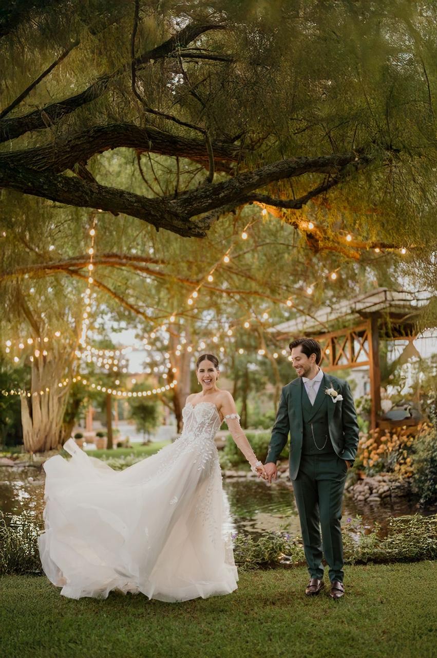 Novios bajo las luces cálidas de los árboles del jardín